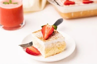 Traditional Colombian tres leches cake topped with whipped cream and fruit